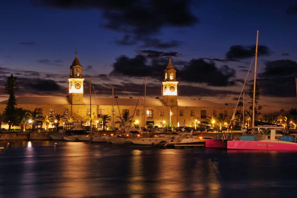 A body of water with buildings behind that are very well lit up.