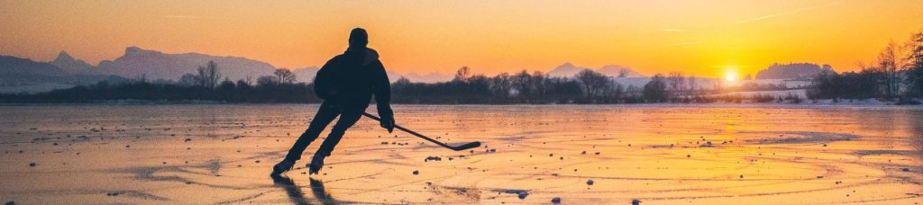 Image of a man skating on ice with a ice hockey stick.