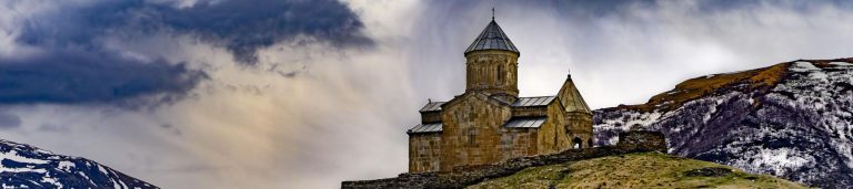 An old building on a hill, with a cloudy background.