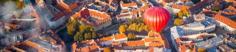 Picture of a hot air balloon flying over the city of Lithuania.