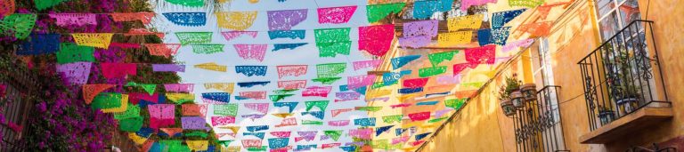 View of colorful streamers hung across buildings in Mexico.